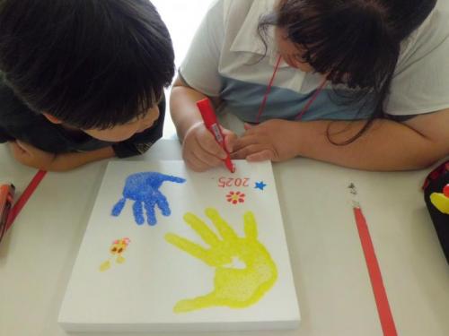 子どもが発砲スチロールに手形をつけたり、絵を描いている。