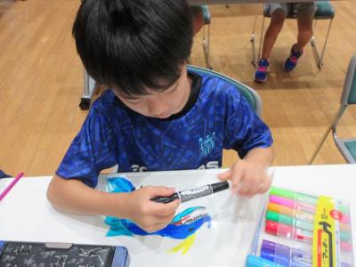 男の子がペンでイラストを描いている様子