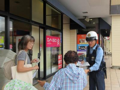 警察官と共同で取手市消費生活展実行委員会がリーフレットを配布している様子