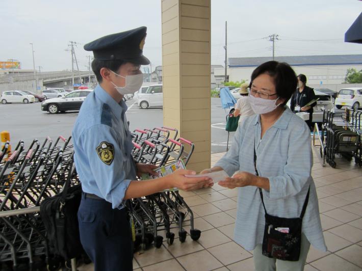 警察官が水色の服を着た女性にチラシを渡している様子