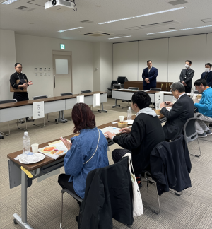 審査員がテーブルに座り、出品者の説明を聞いている様子