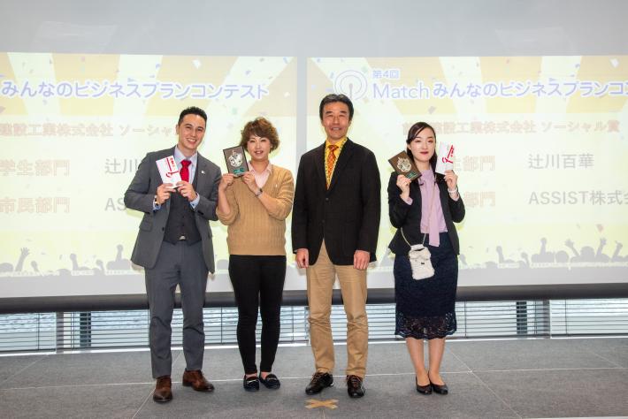 前田建設ソーシャル賞受賞者の記念写真。盾や賞の紅白封筒を手にした4人の人の記念写真の画像。
