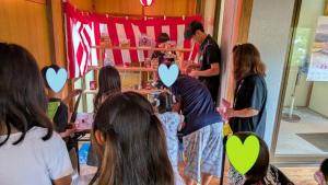 夏祭りで射的を担当する体験参加者たち