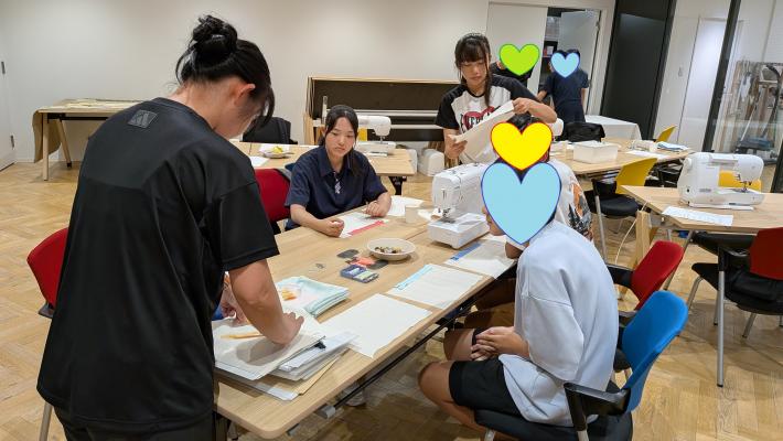 廃材のカーテン生地でポシェットの作りかたを教わる様子