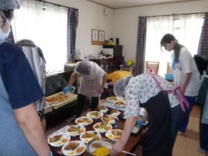 子ども食堂で料理の配膳を手伝う体験参加者の様子