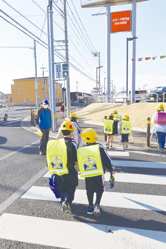 横断歩道を渡る子ども達を大人が見守っている様子