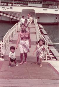 富永さんお子さんが小さいころの旅行写真。女性と子どもが船から降りている様子。