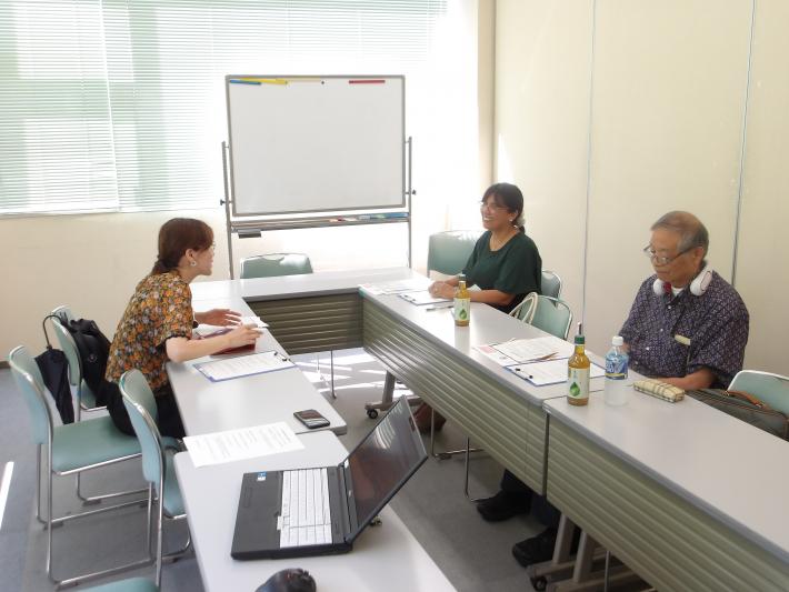 斎藤リリアナさんと国際交流協会の志村会長に取材する下園さんの画像
