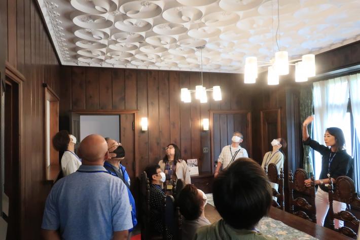 旧渡辺甚吉邸のダイニングで、白い装飾が施された天井を見上げる参加者たちの写真