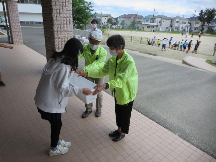 永山小学校で人権擁護委員が児童にプランターを渡している