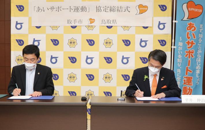 藤井市長と平井鳥取県知事が協定書に署名している写真