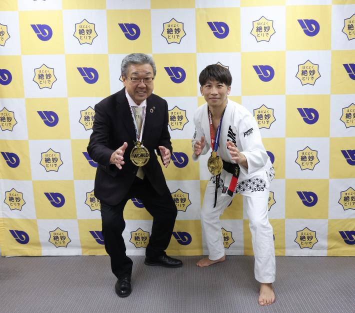 市長と選手が格闘技のポーズをとって並んでいます