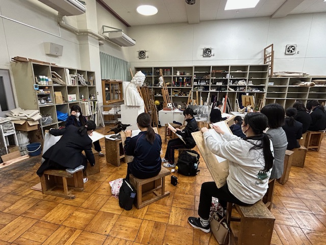 小中学生が石膏像を囲んで絵を描いている。