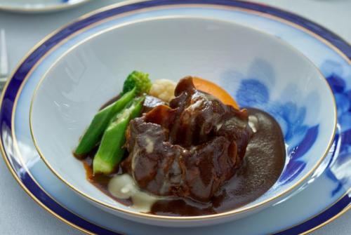 牛テールの赤ワインを拡大した写真。おいしそうな赤赤としたテールの煮込みが映っている